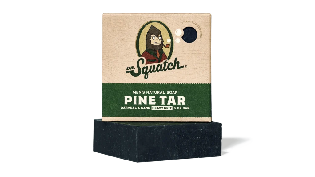 Dr. Squatch Pine Tar Men's Natural Soap 5 oz bar resting below its cardboard box featuring the Sasquatch logo.